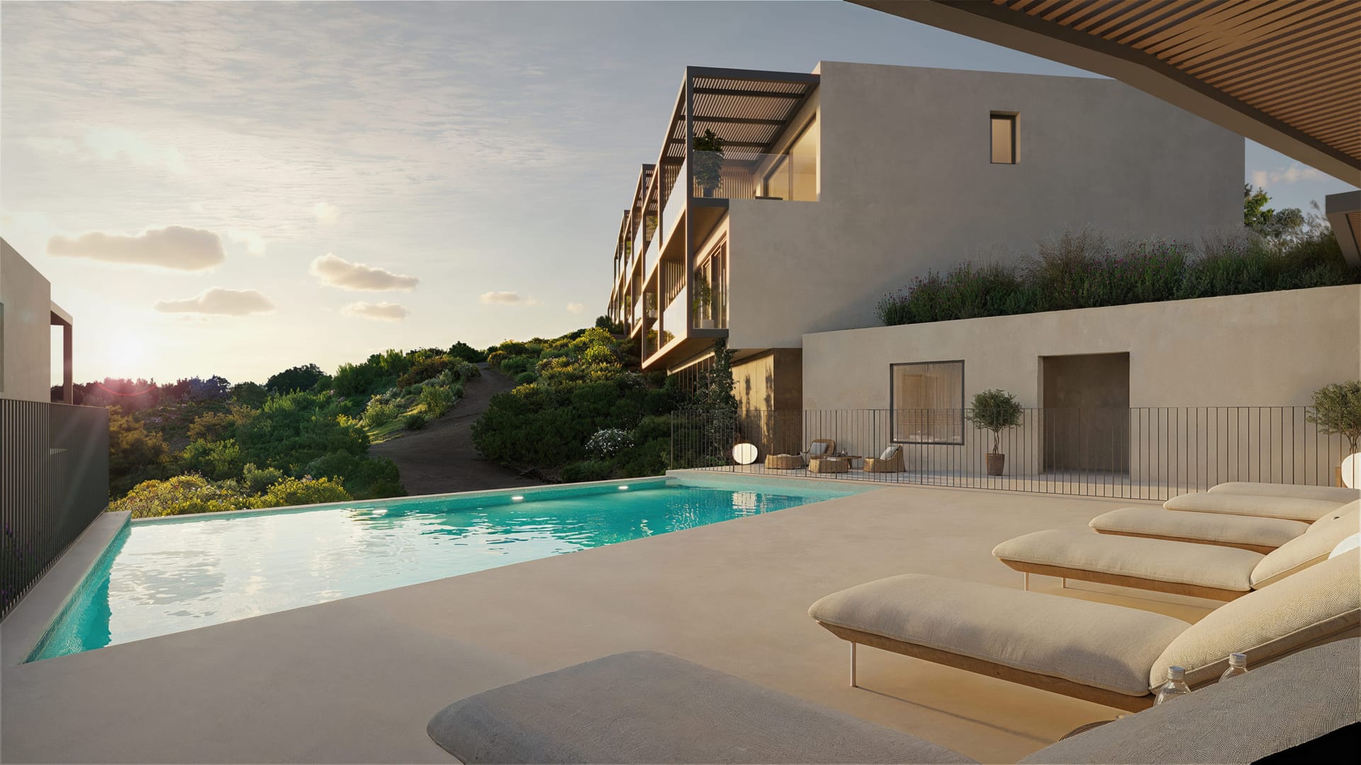 One of the other pools at dusk, with sun loungers along its deck and townhouses above it. Veridian, El Higuerón, Fuengirola.