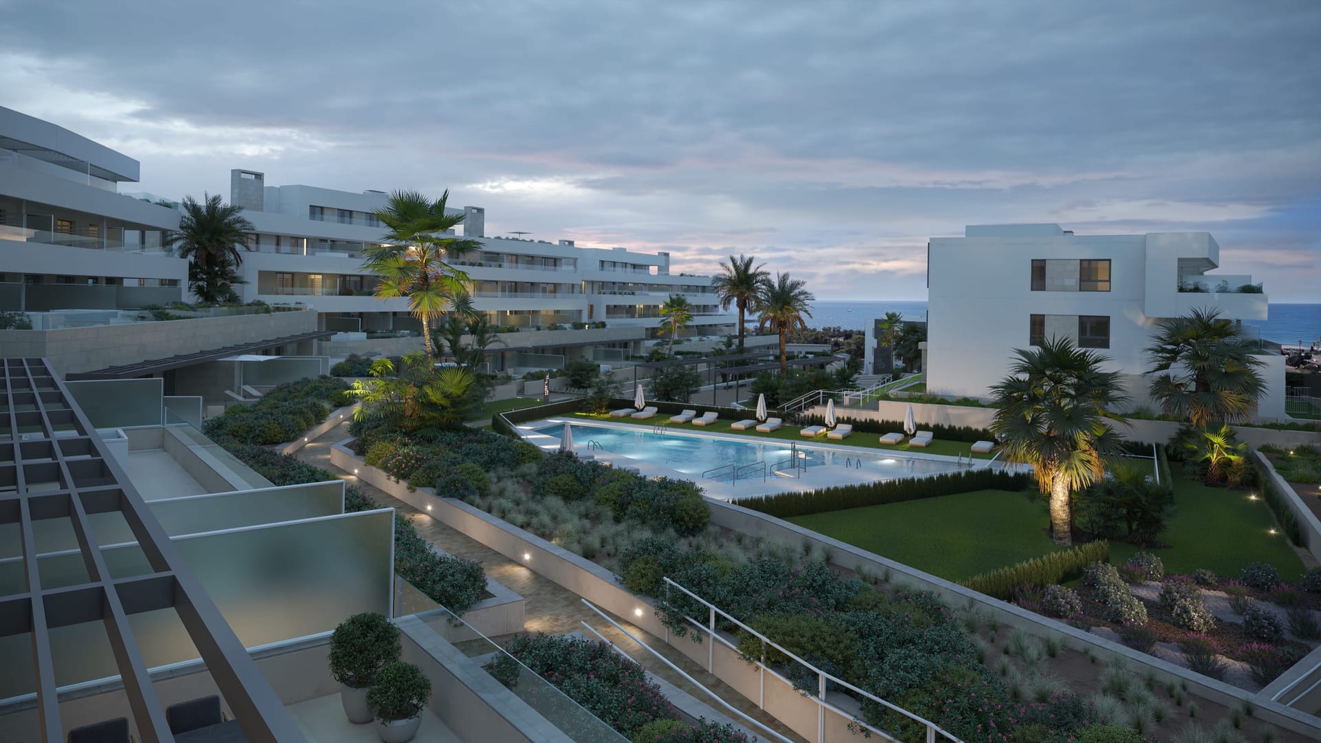 The gardens and a pool at dusk, seen from a terrace above, with the sea on the horizon. Zenity Blau II, La Gaspara, Estepona.