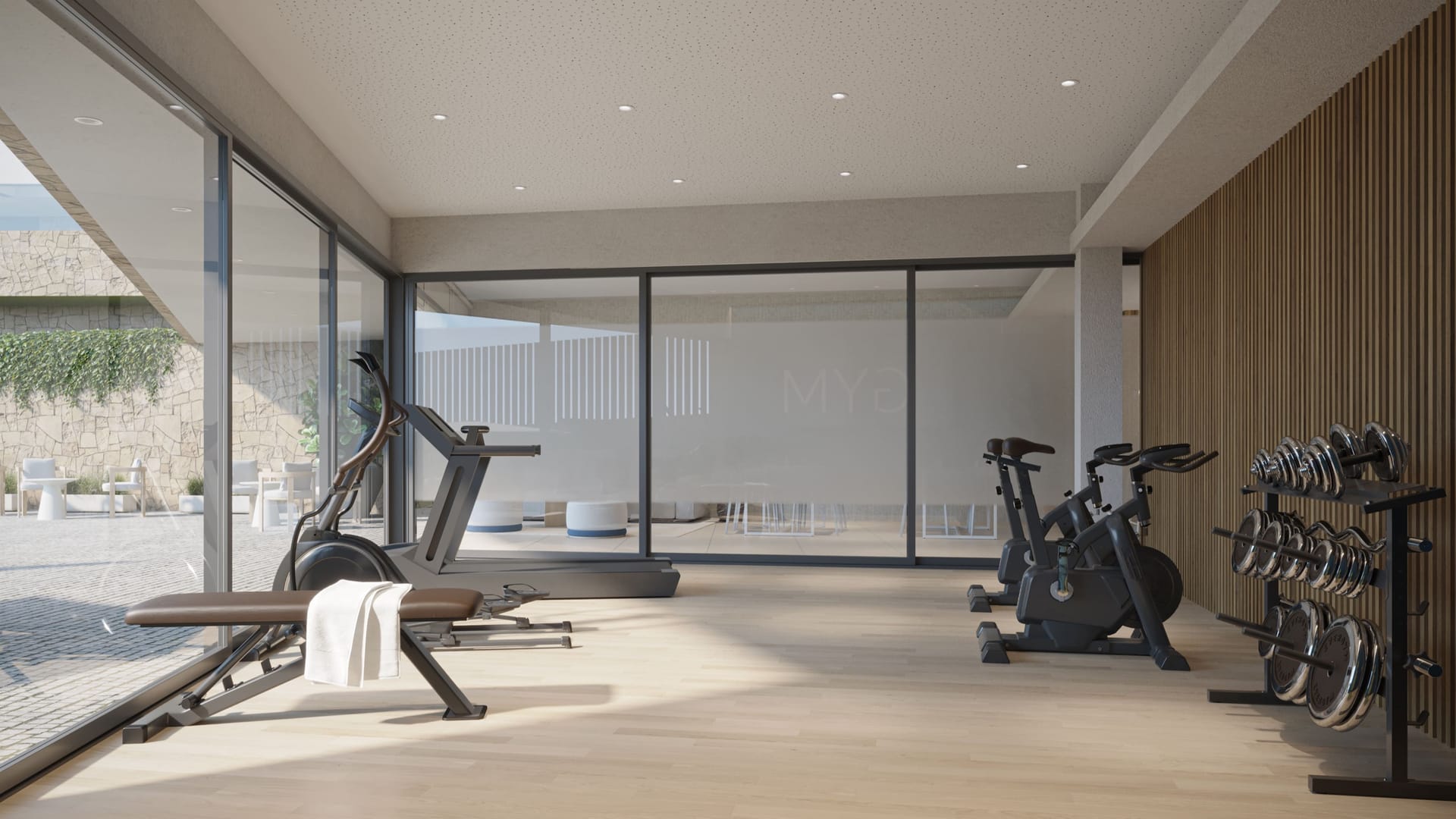 The gym, with exercise bikes, a running machine and a rack of weights beside walls of glass. Zenity Indigo, La Gaspara, Estepona.