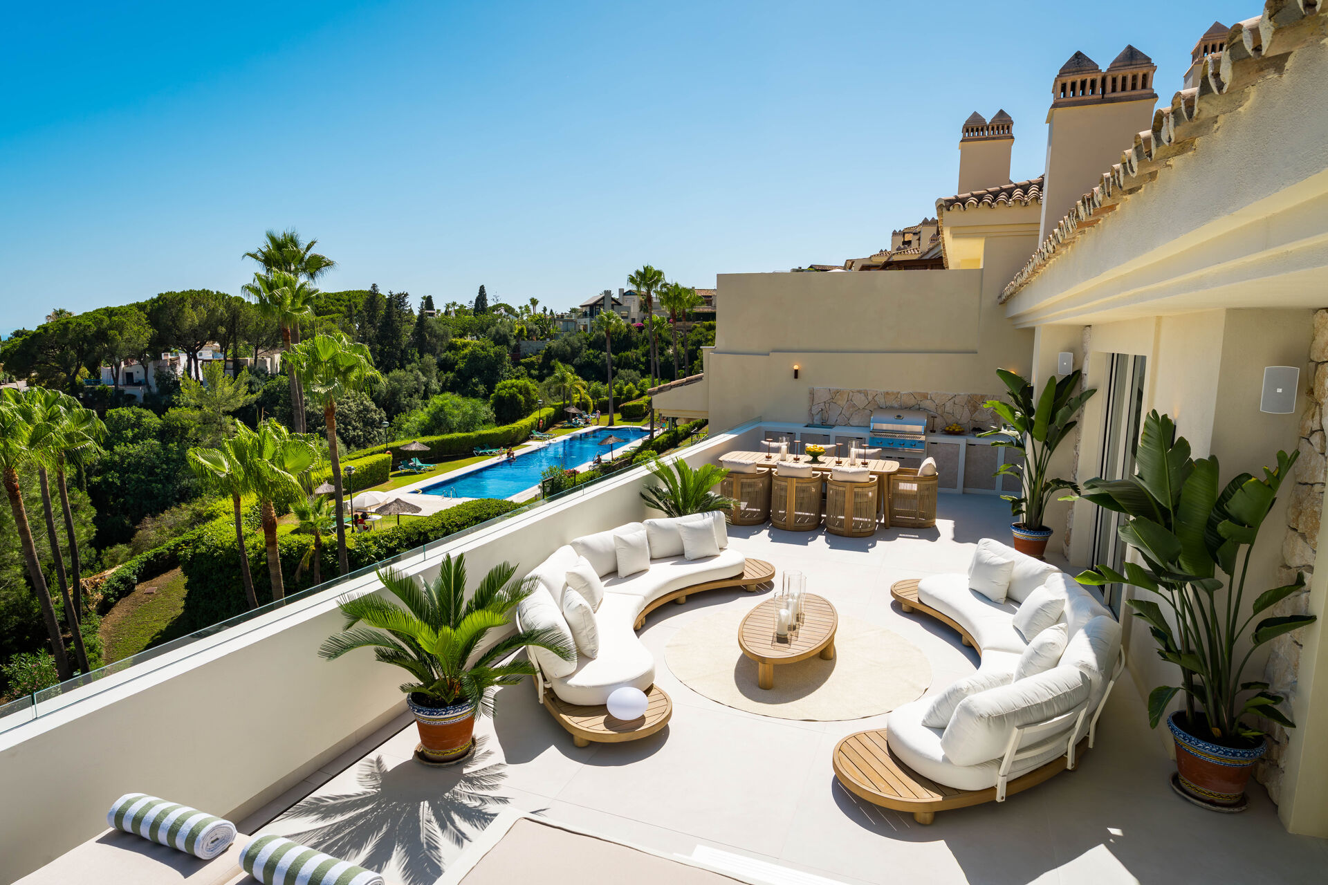 The main terrace with curved sofas and an outdoor kitchen, above the communal pool and gardens.