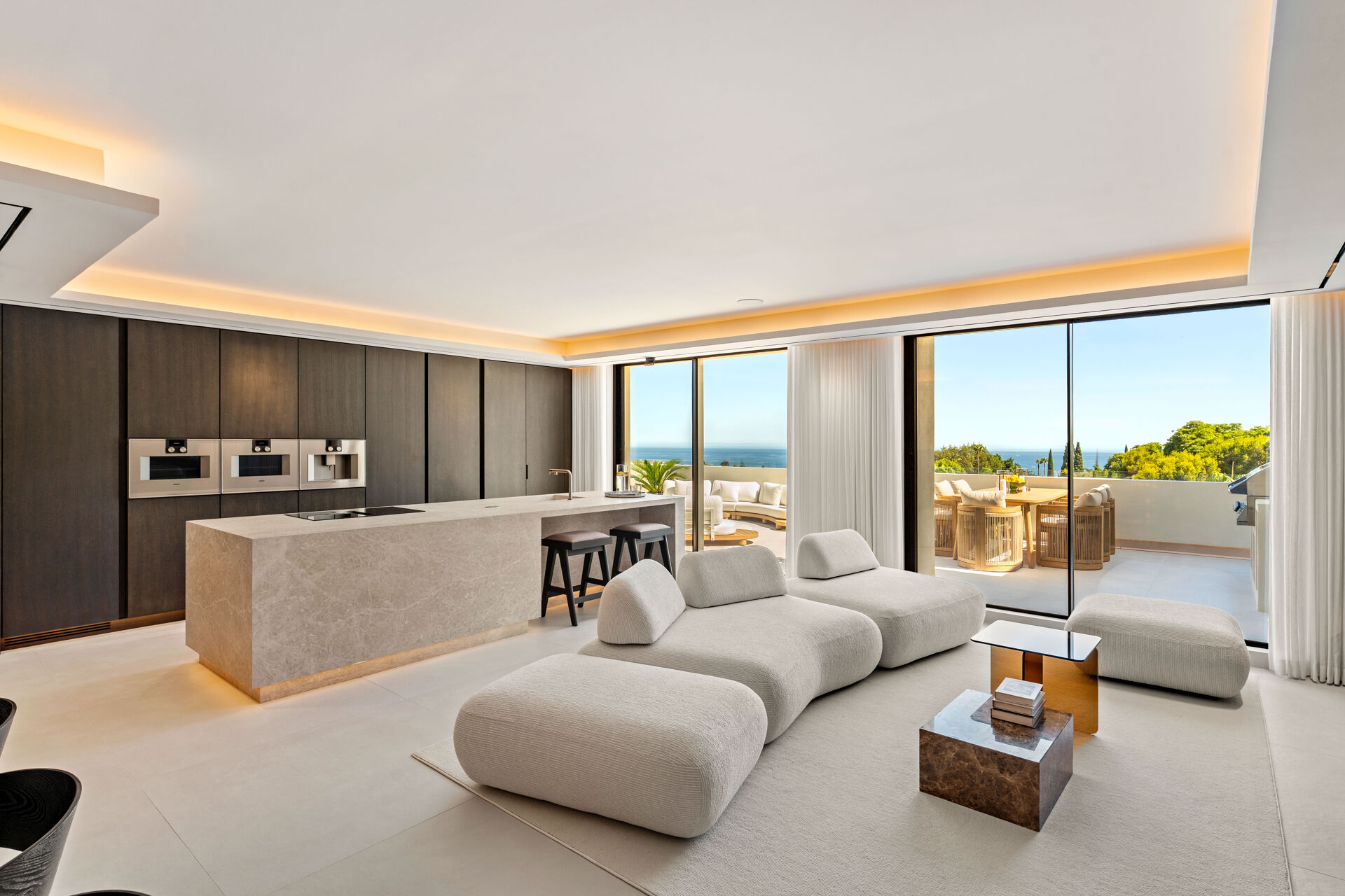 The living room and the kitchen in one open space, with a long island, three built-in ovens and glass doors onto the terrace and the sea.