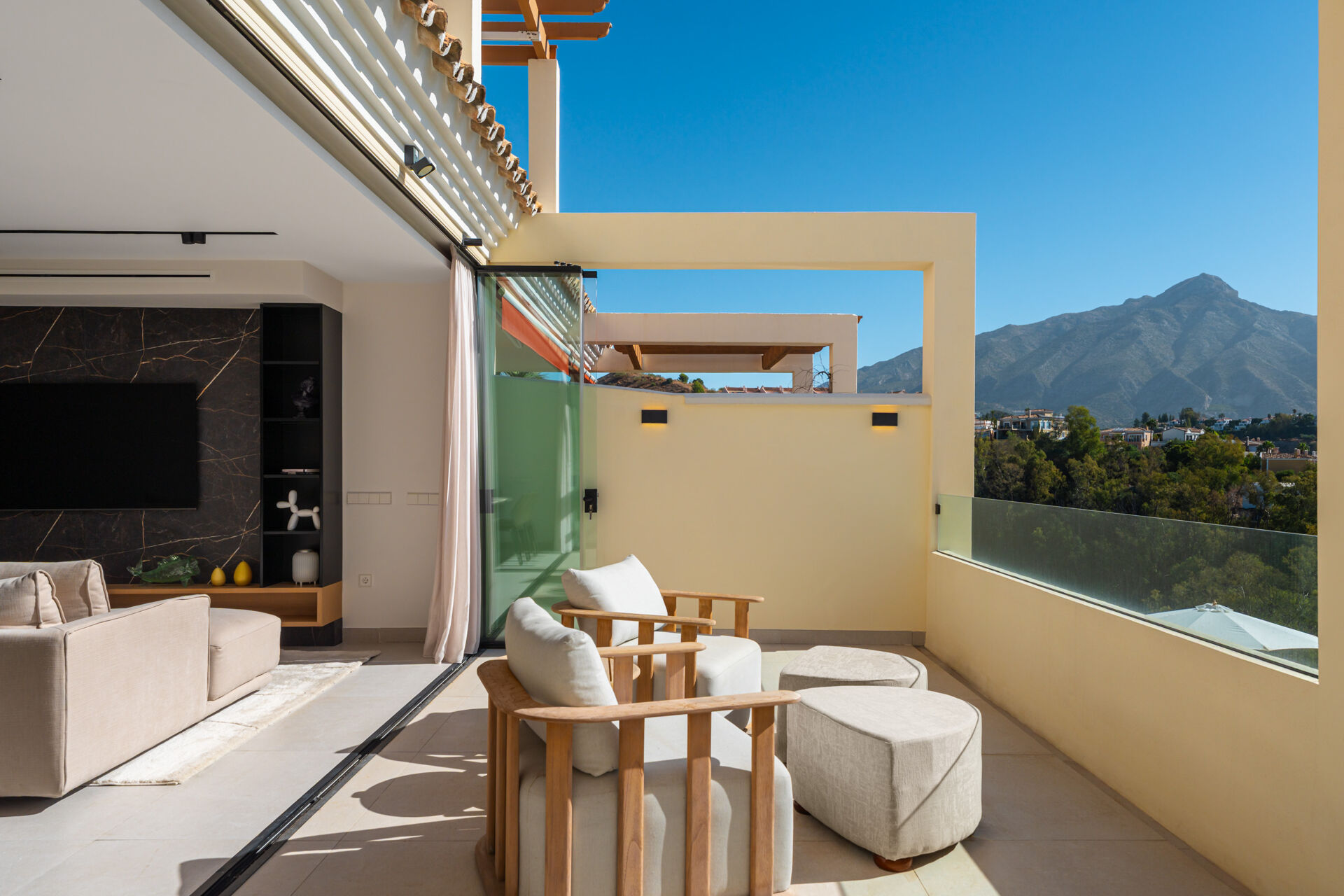 The terrace beside the lounge, with two armchairs and footstools behind a glass balustrade, and La Concha mountain to the right.