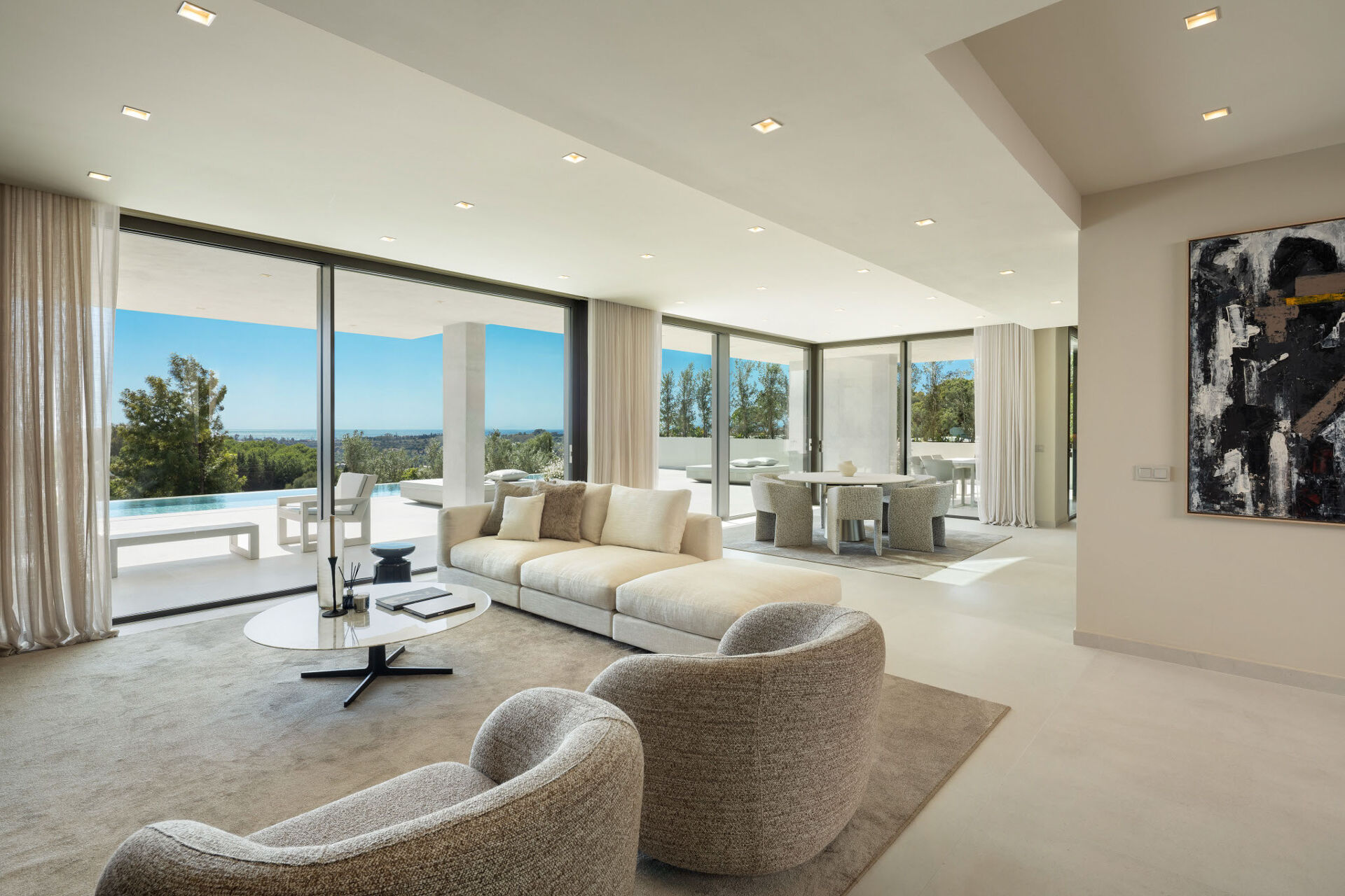 The living room, with a sofa and two armchairs, and sliding glass doors to the terrace.