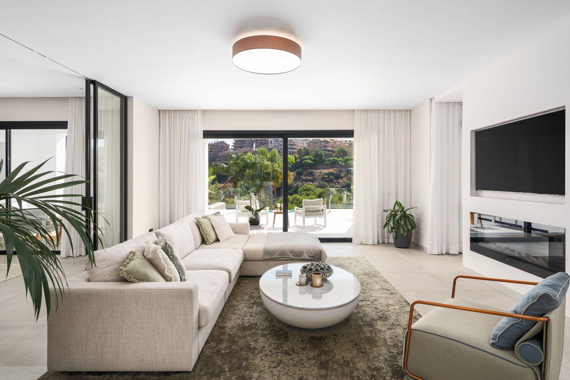 The living room, with a corner sofa, a fireplace and glass doors to the terrace.