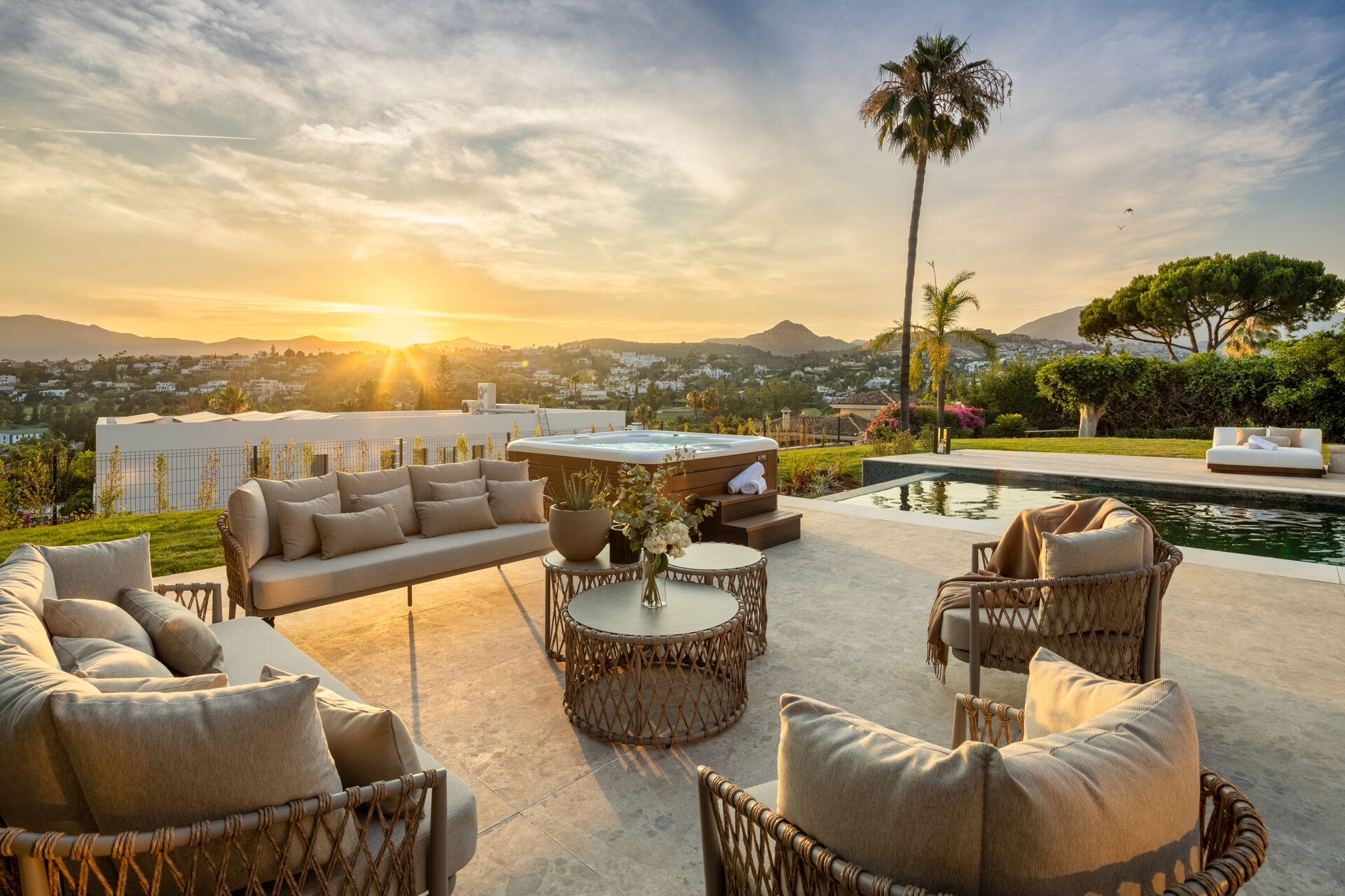 The terrace at sunset, with a hot tub, the swimming pool and views over the surrounding houses and hills.