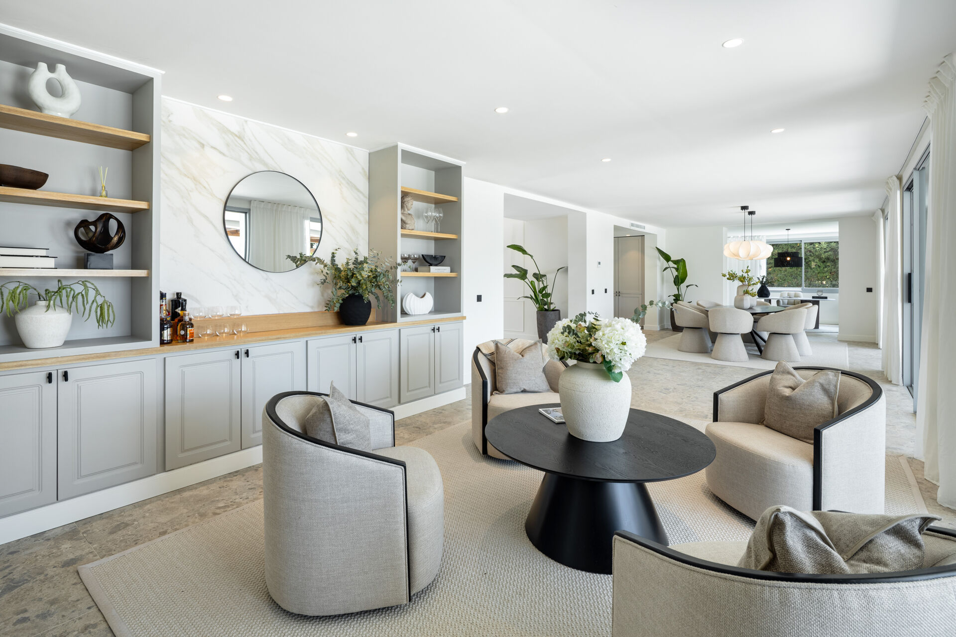 The open-plan living room with built-in shelving, four armchairs and a round table, and the dining area beyond.