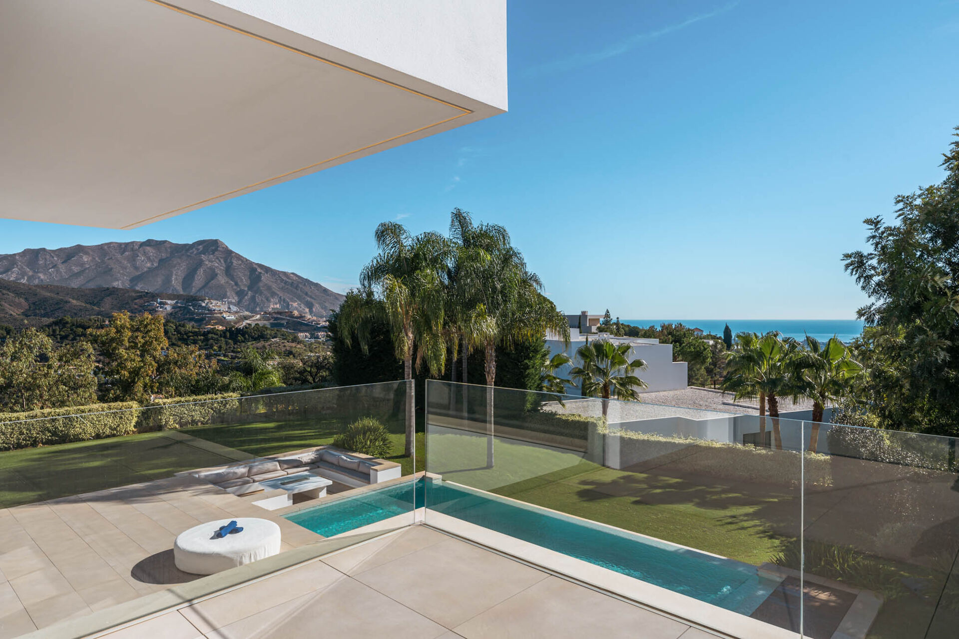 The view from the upper terrace over the pool, the sunken seating and the palms to the mountain and the sea.
