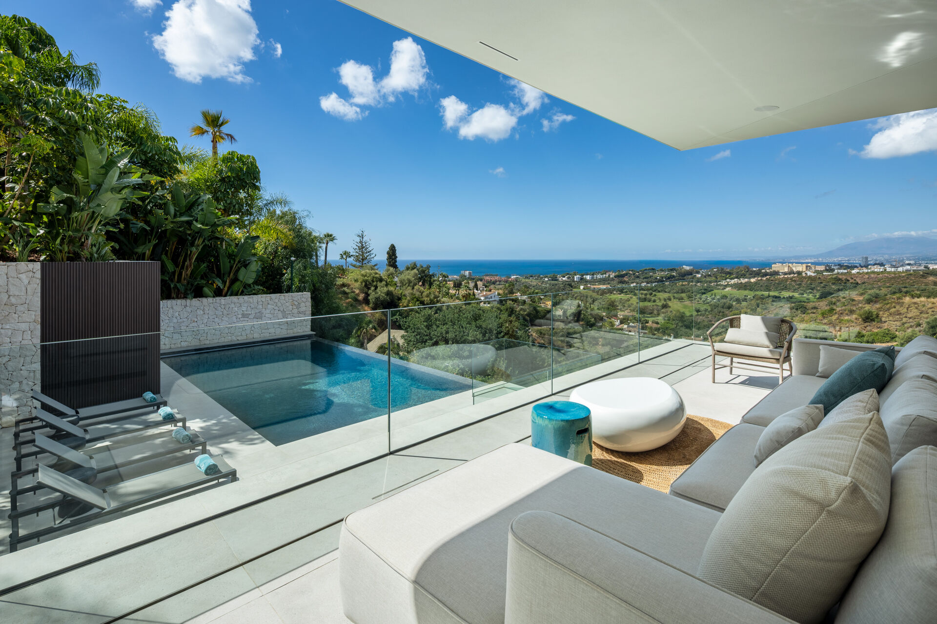 The upper terrace, with a sofa, a small plunge pool and a glass balustrade, looking over the golf course to the sea.