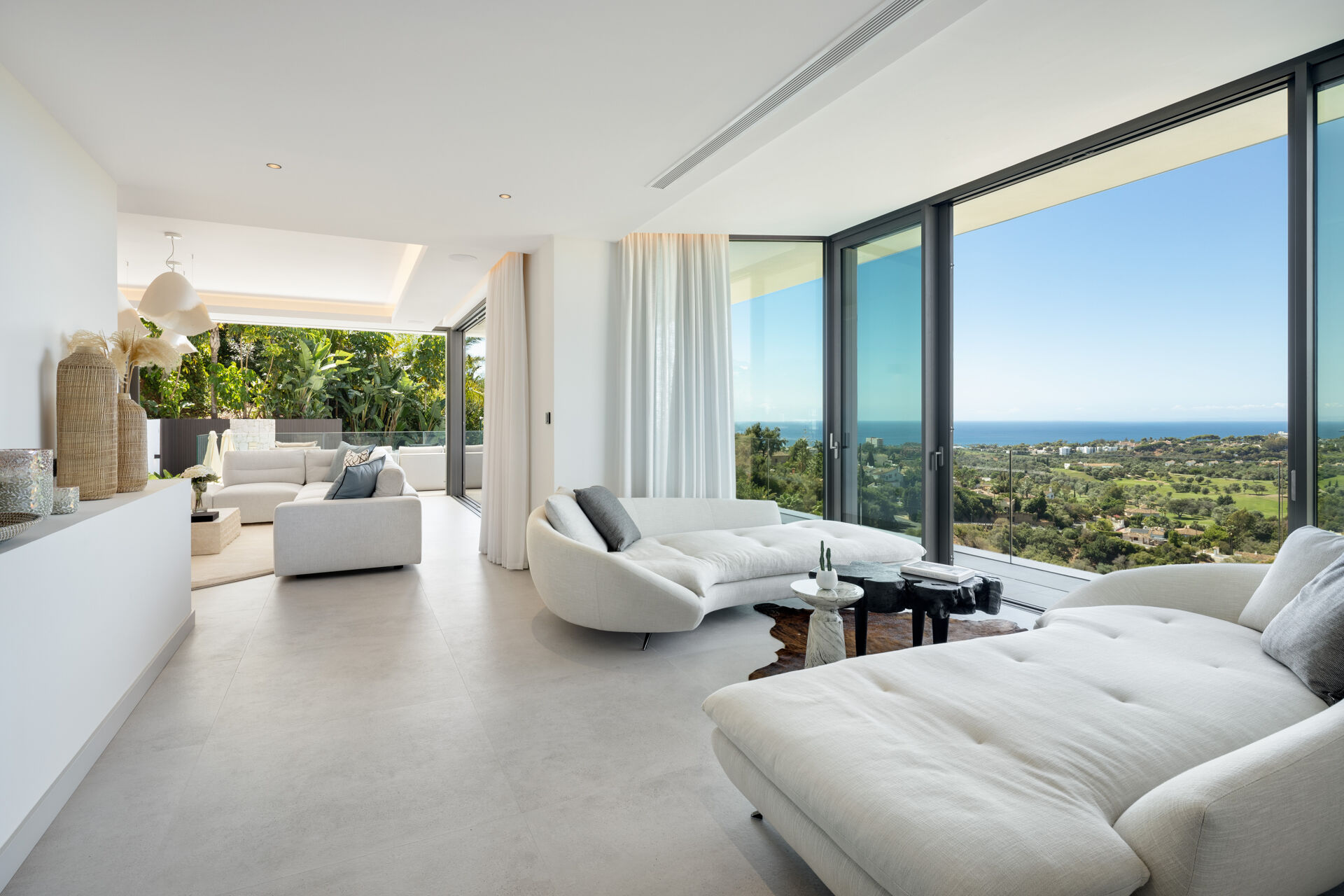 The living room, with a corner sofa and glass doors that look out to the sea and a golf course.