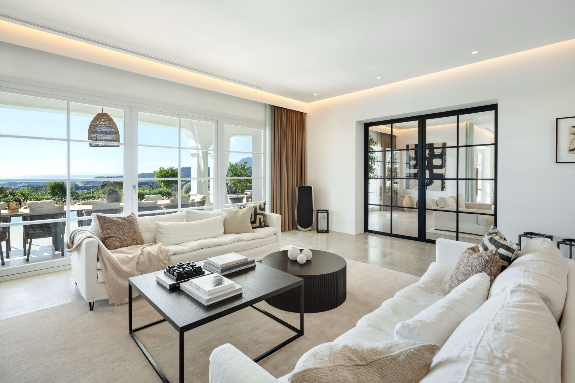 The living room, with two white sofas and large windows looking out over the terrace and the valley.
