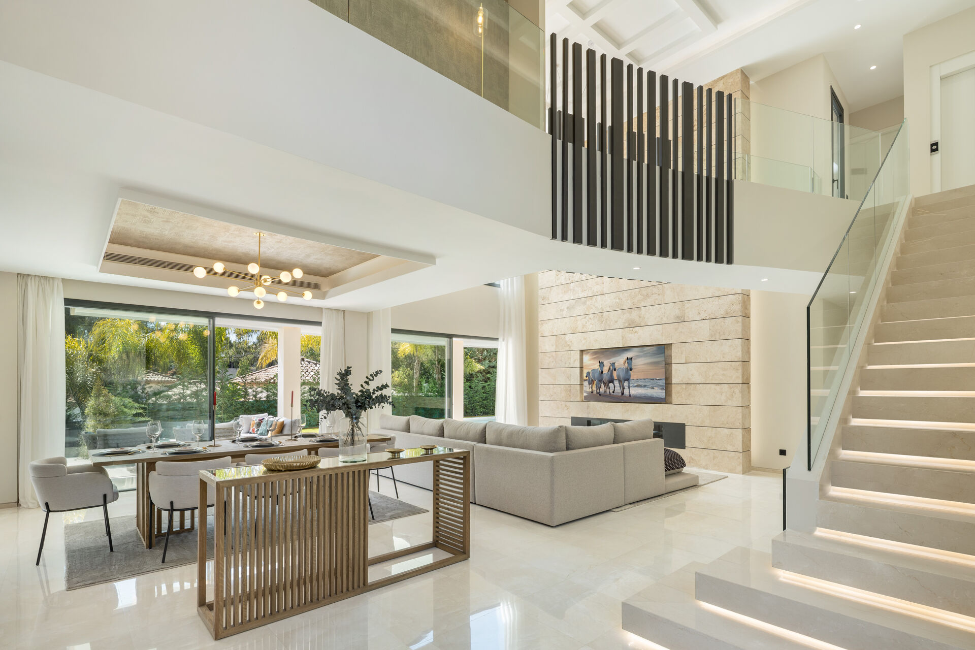 The living and dining area, with the glass-sided staircase rising to the upper floor.
