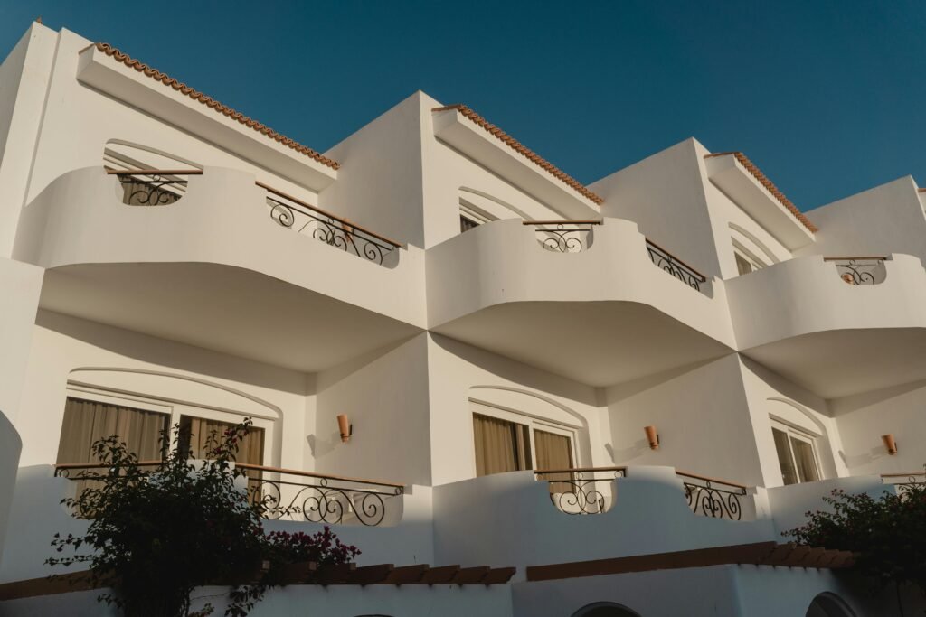 Elegant white Mediterranean building with ornate balconies under a clear blue sky.